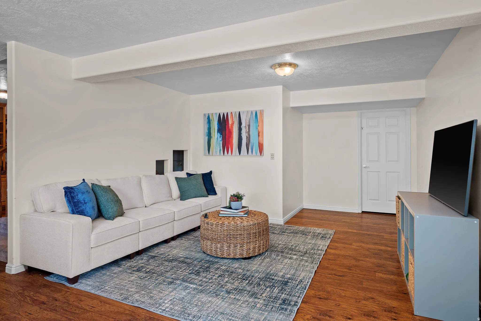 Wood-finish flooring, recessed ceiling lighting, light-toned wall finishes, and a six-panel interior door