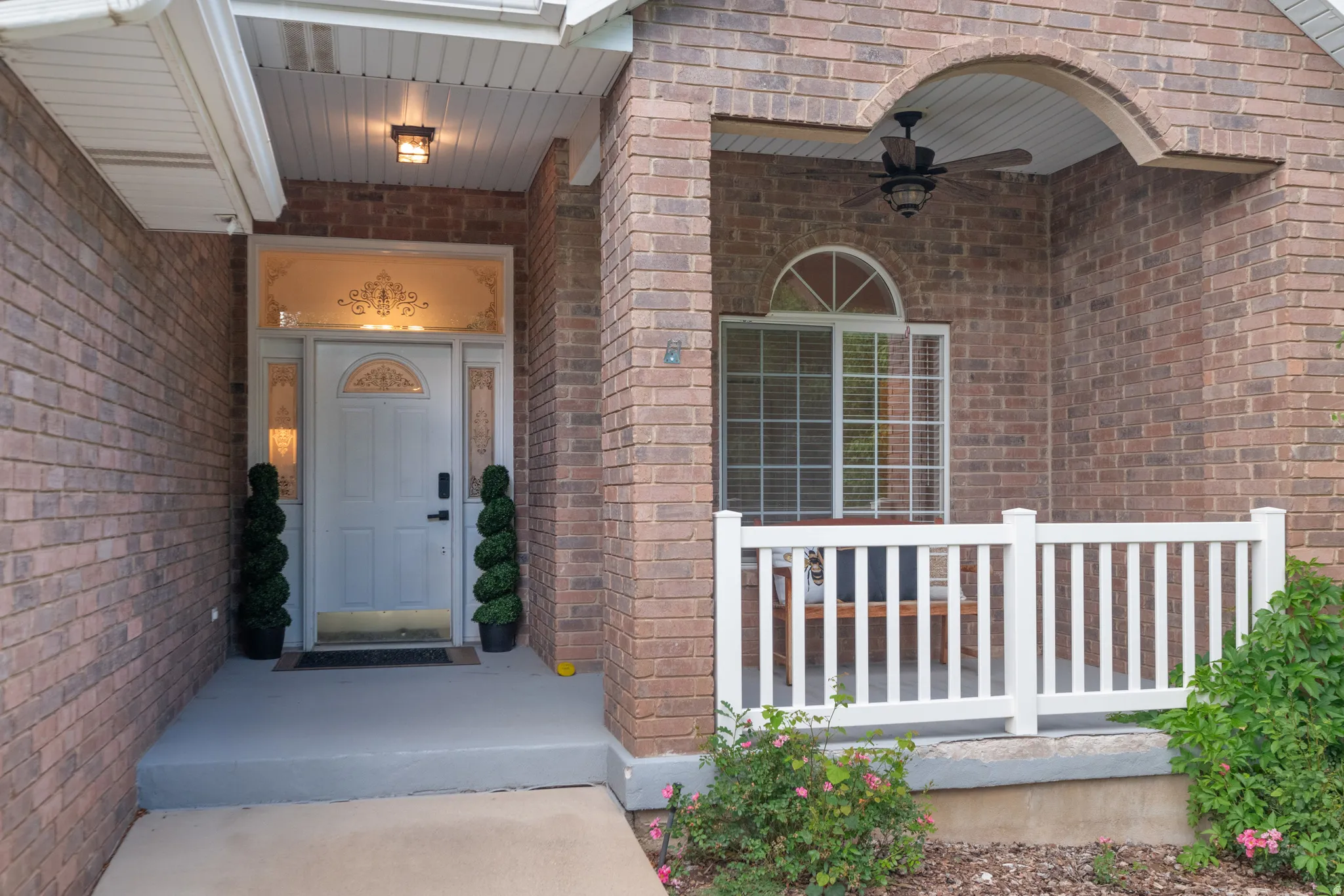 Brick exterior with a covered porch, white railing, and an arched window