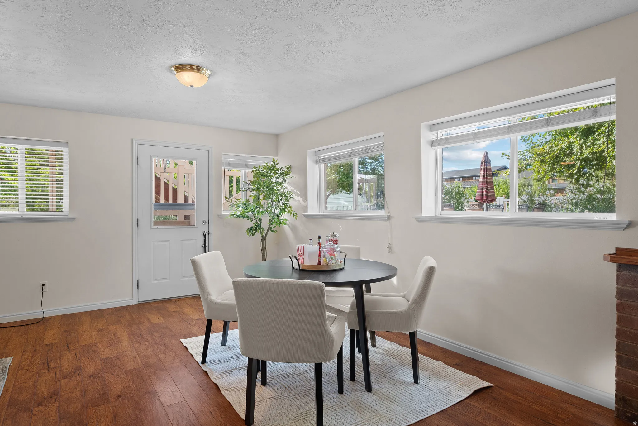 Wood-finish flooring, multiple windows, white door with glass panel, recessed lighting, and a brick-finish architectural element