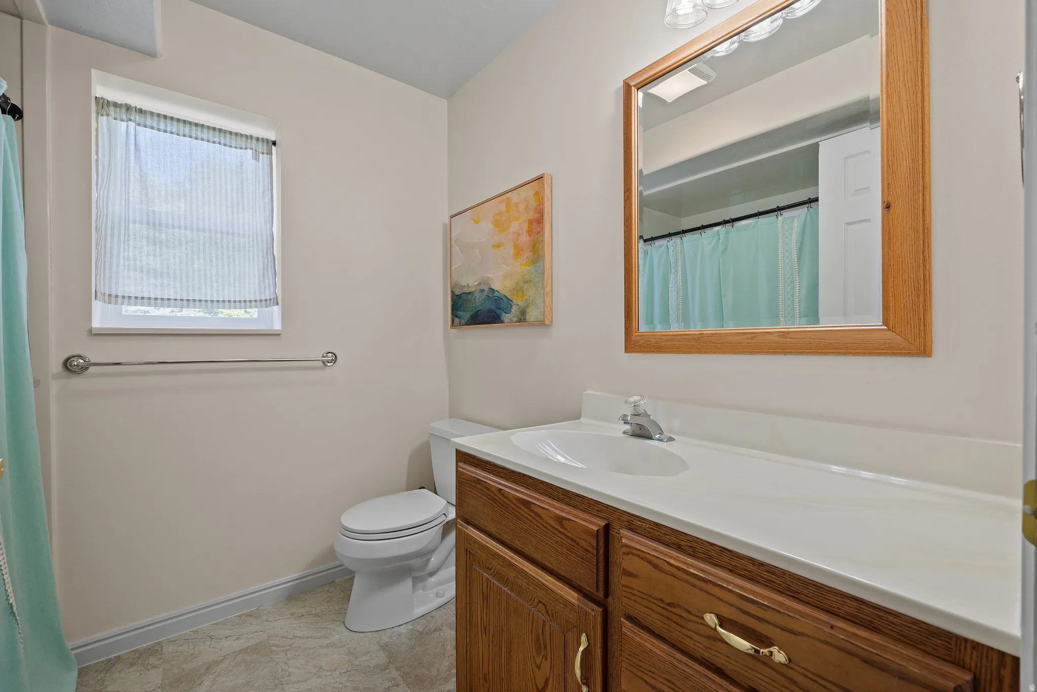 Bathroom featuring a single vanity with wood-finish cabinetry, a white countertop, and an integrated sink