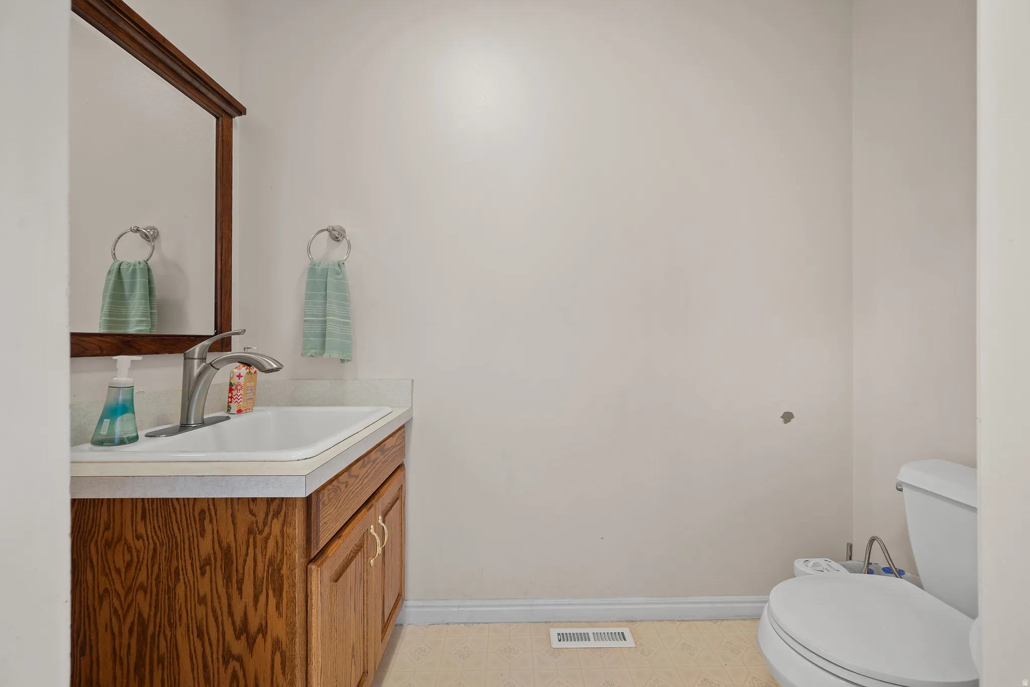 Vanity with wood-finish cabinetry, integrated sink, and a framed mirror