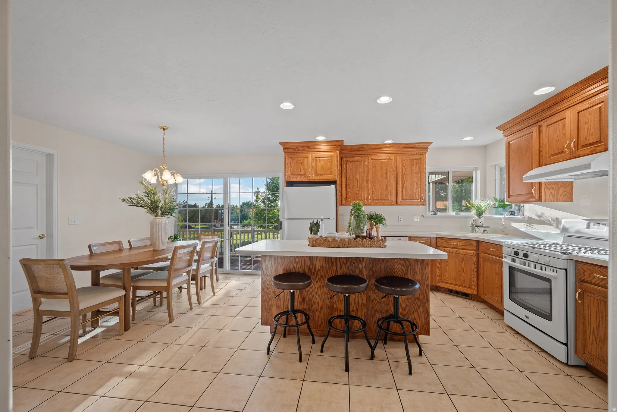 Kitchen featuring light wood-finish cabinetry, white countertops, tile flooring, a center island with bar seating, and sliding glass doors