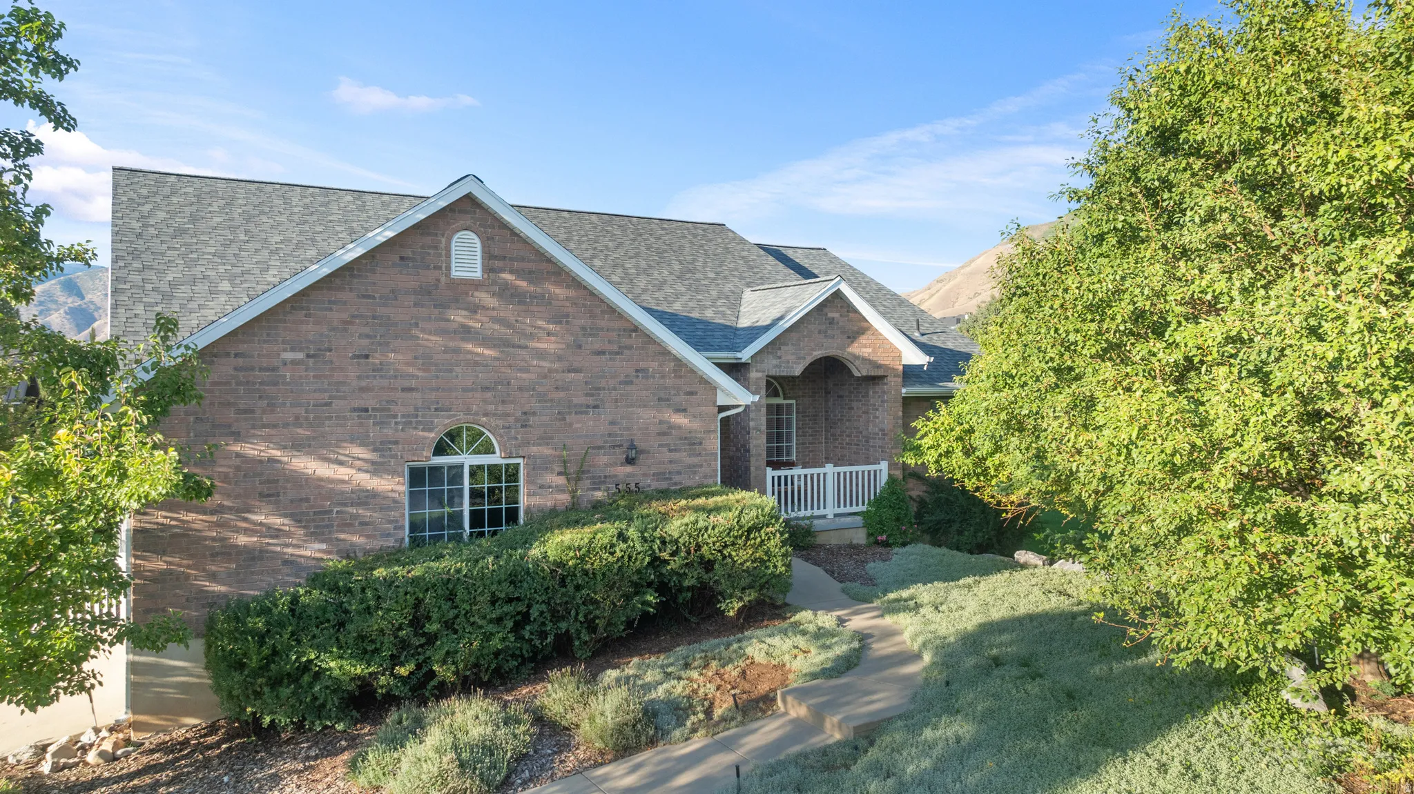 Brick exterior with a gabled roofline, arched window, and covered entryway with white railings