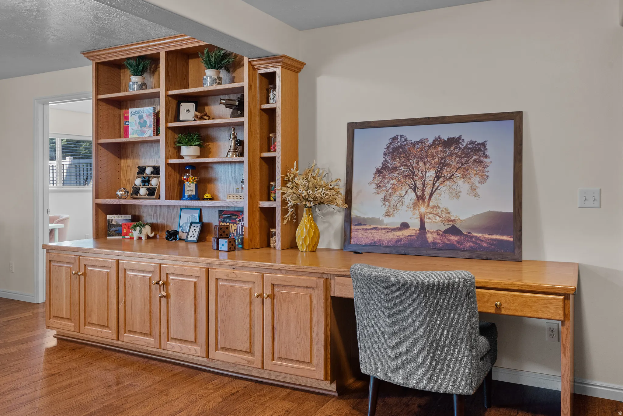 Built-in wood cabinetry with brass hardware, integrated shelving, wood-finish flooring, and a dedicated desk area