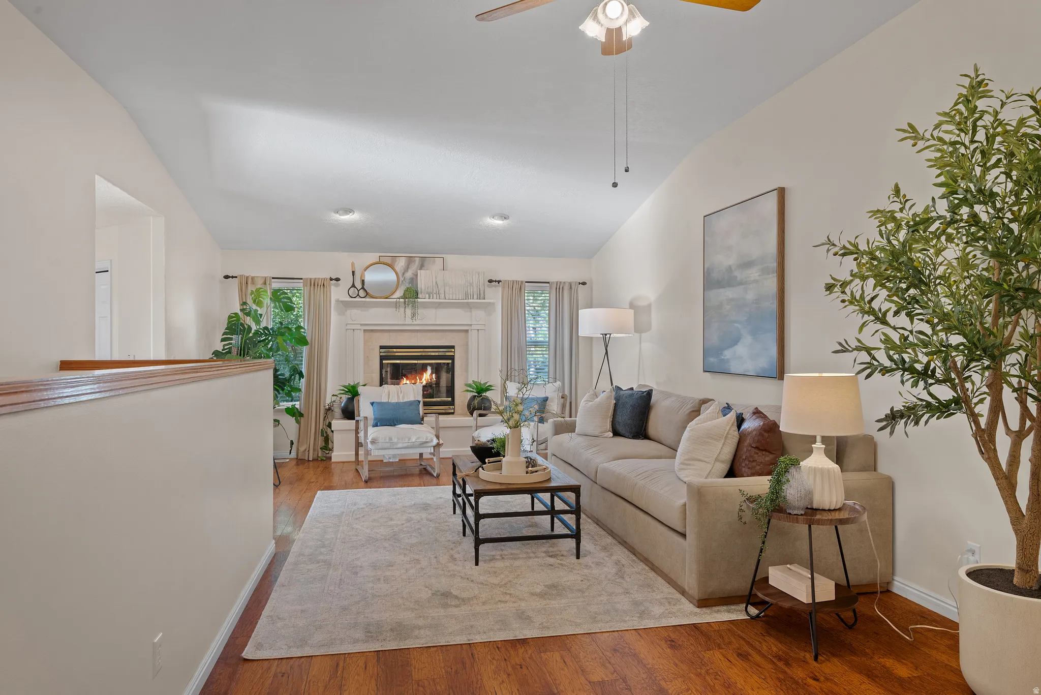Vaulted ceiling, wood-finish flooring, fireplace, recessed lighting, and a ceiling fan