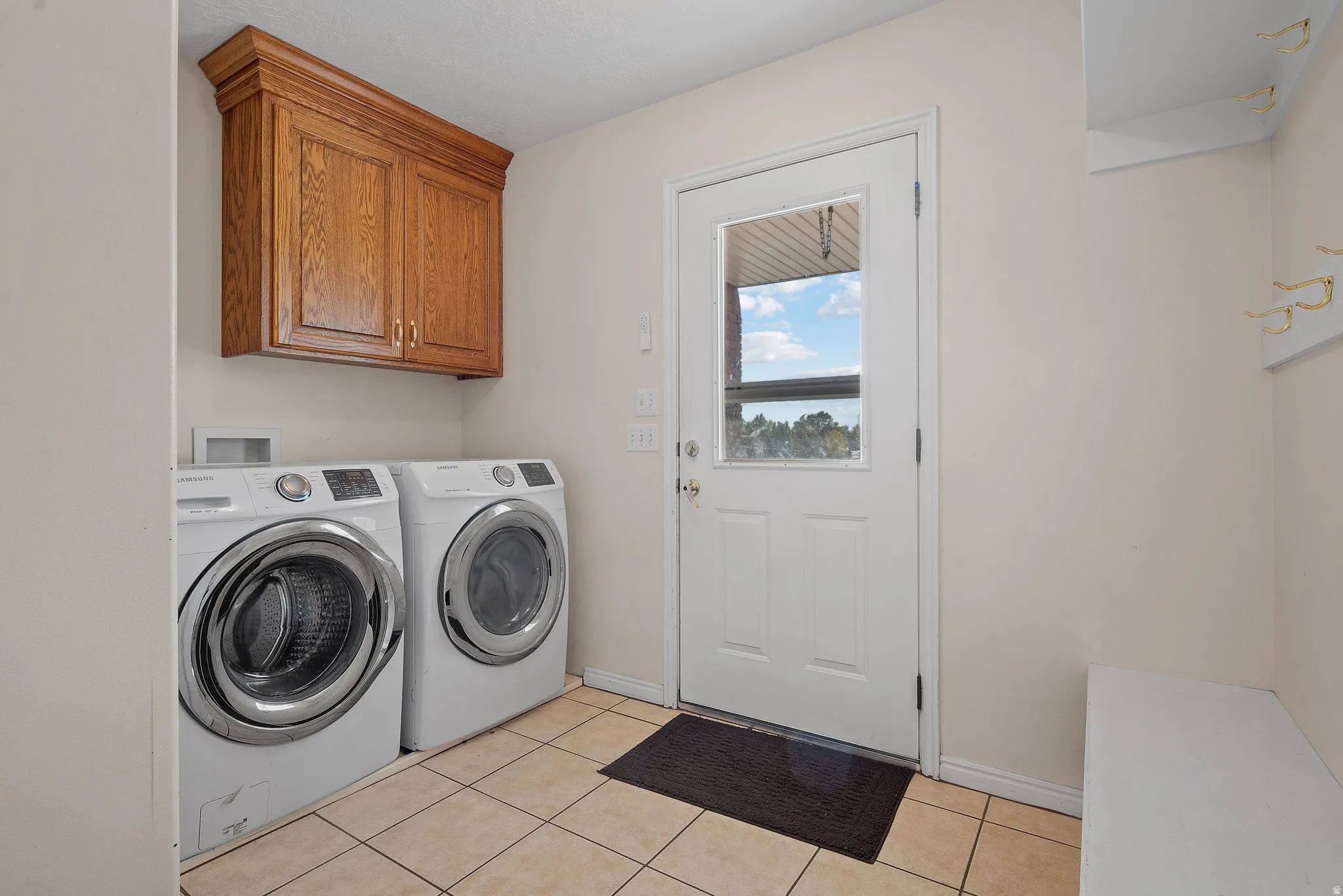 Wood-finish cabinetry, ceramic tile flooring, built-in coat hooks, and a built-in bench