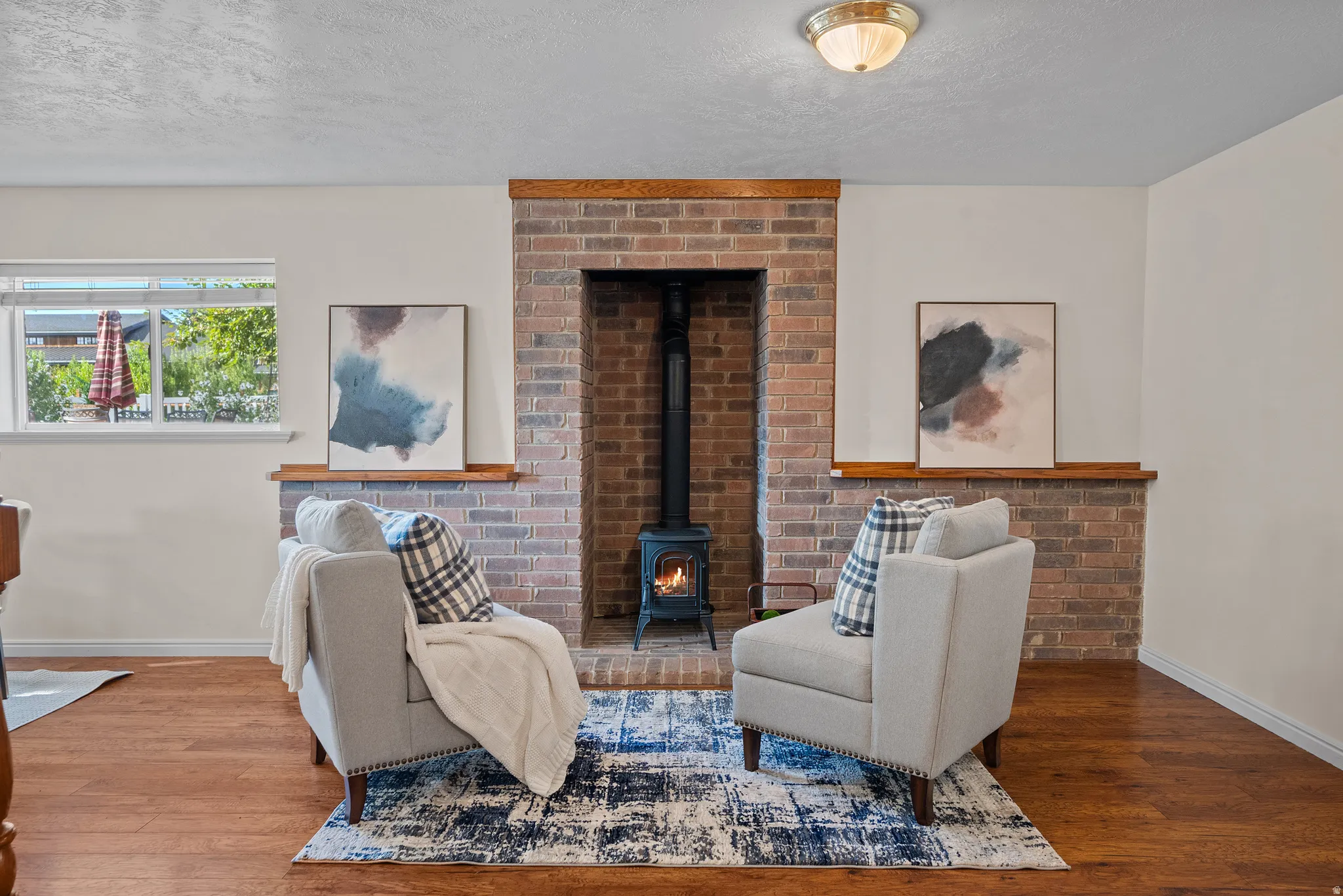 Brick fireplace with a black wood-burning stove, solid wood mantel, and wood-finish flooring