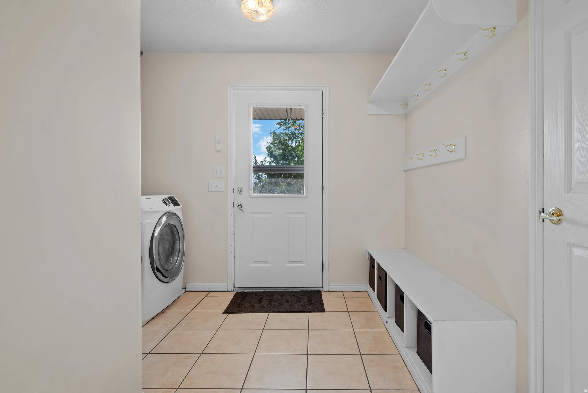 Entryway with tile flooring, built-in storage bench, and coat racks