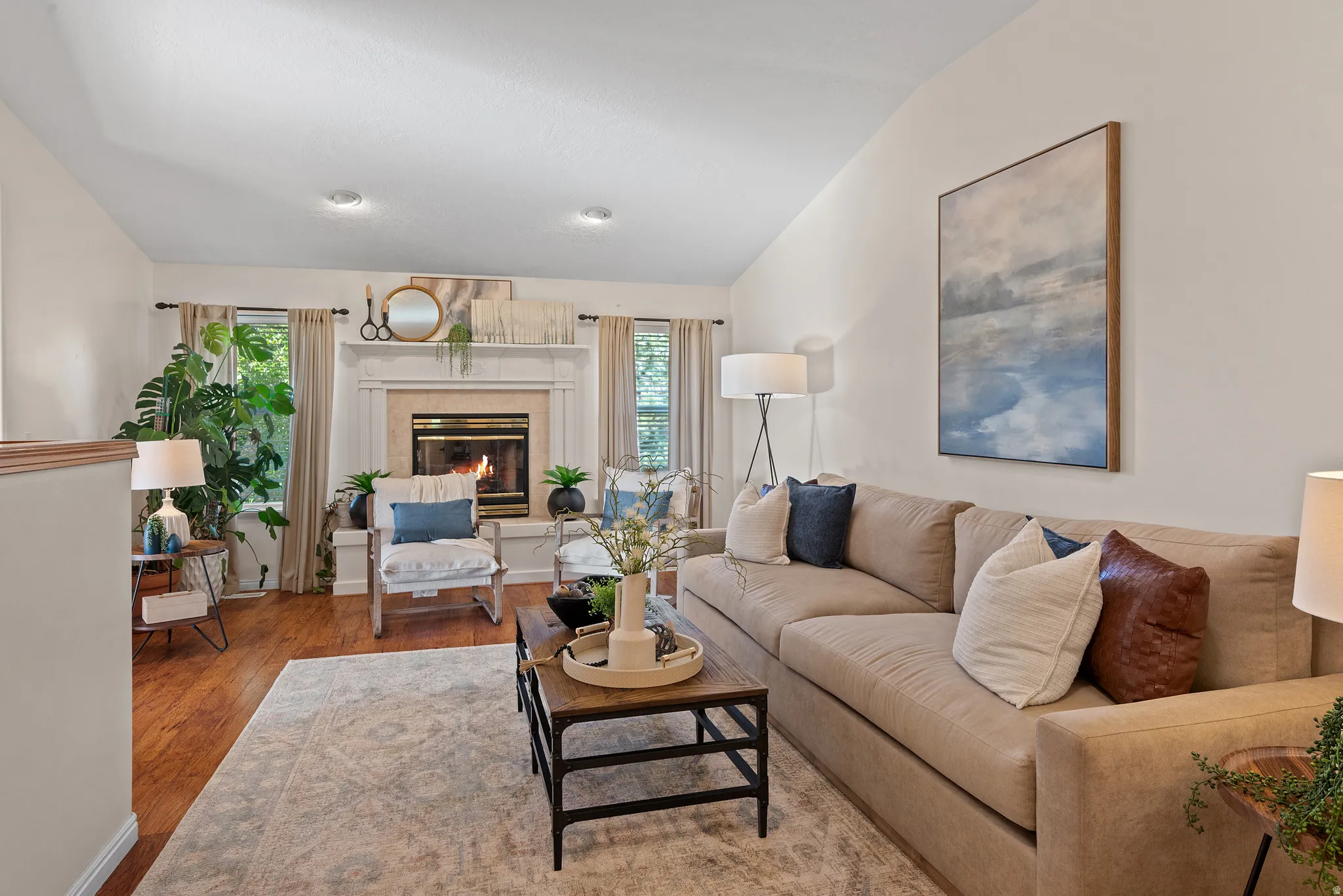 Vaulted ceiling, wood-finish flooring, recessed lighting, fireplace with mantel, and large window with natural light