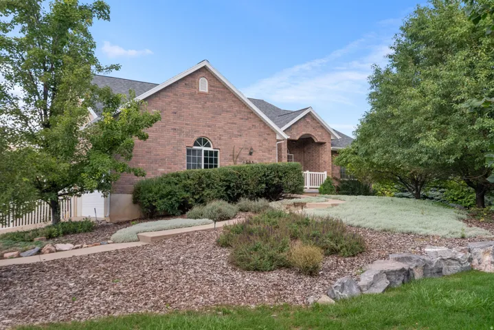 Brick exterior with an arched entry, a gabled roof, and a mature tree