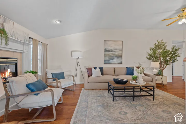 Spacious living area featuring wood-finish flooring, a fireplace with a white mantel, and recessed ceiling lighting