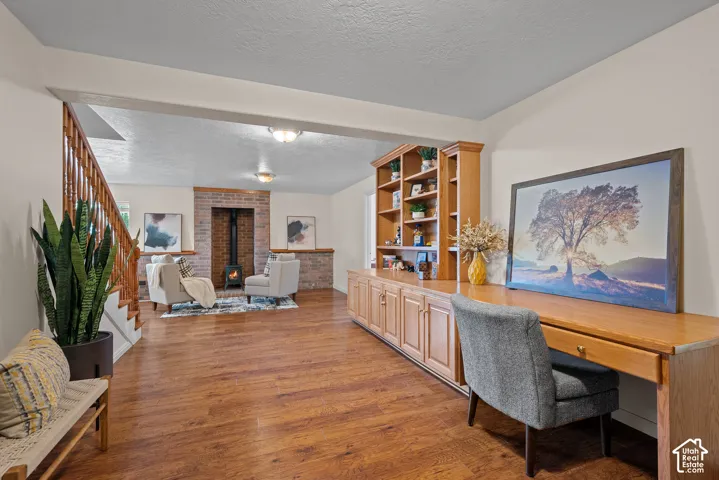 Wood-finish flooring throughout, built-in shelving, wooden staircase with balusters, exposed brick fireplace, and integrated desk