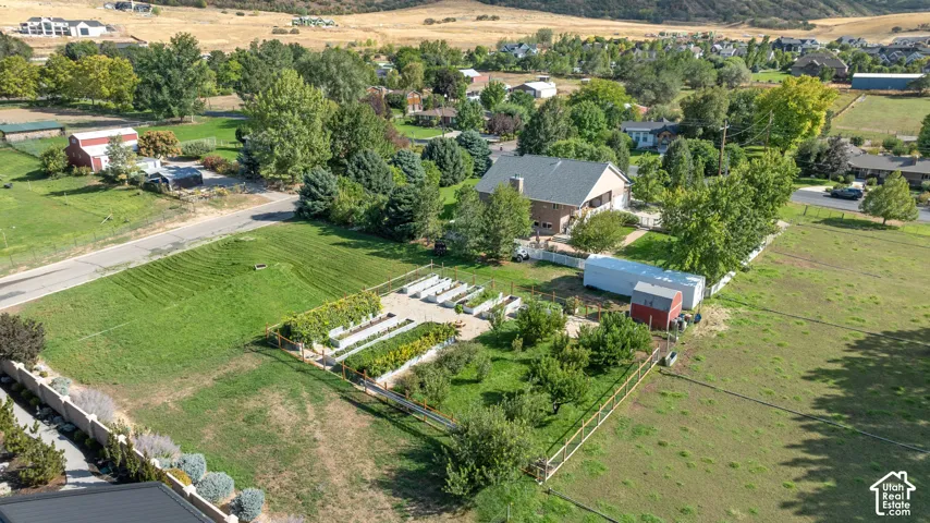 Expansive property featuring a cultivated garden, mature trees, and a brick exterior dwelling with a gray roof