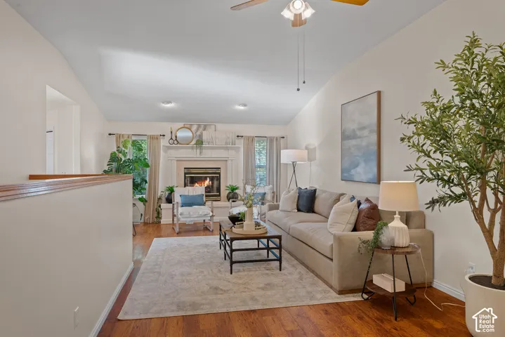 Vaulted ceiling, wood-finish flooring, fireplace, recessed lighting, and a ceiling fan