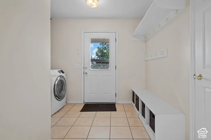 Entryway with tile flooring, built-in storage bench, and coat racks