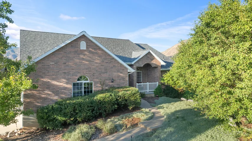 Brick exterior with a gabled roofline, arched window, and covered entryway with white railings