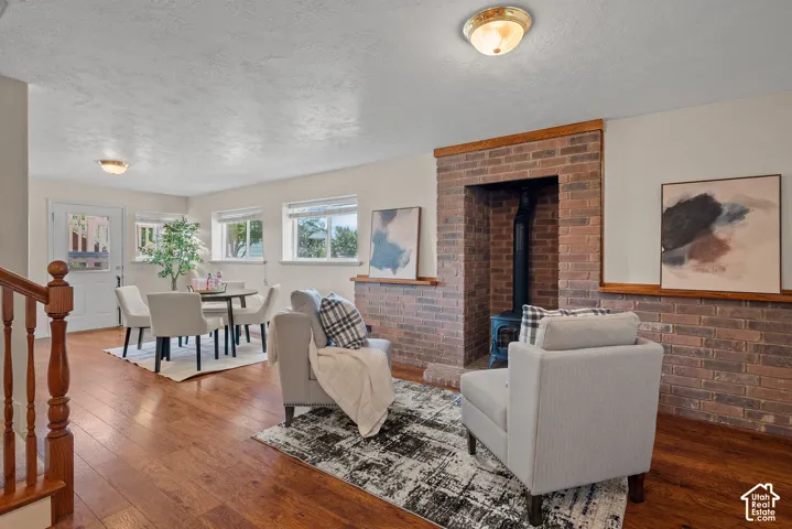 Wood-finish flooring throughout, brick accent wall with fireplace, multiple windows, and a glass-paneled door
