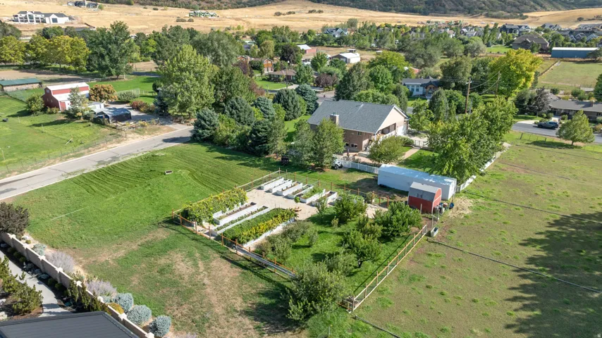 Expansive property featuring a cultivated garden, mature trees, and a brick exterior dwelling with a gray roof