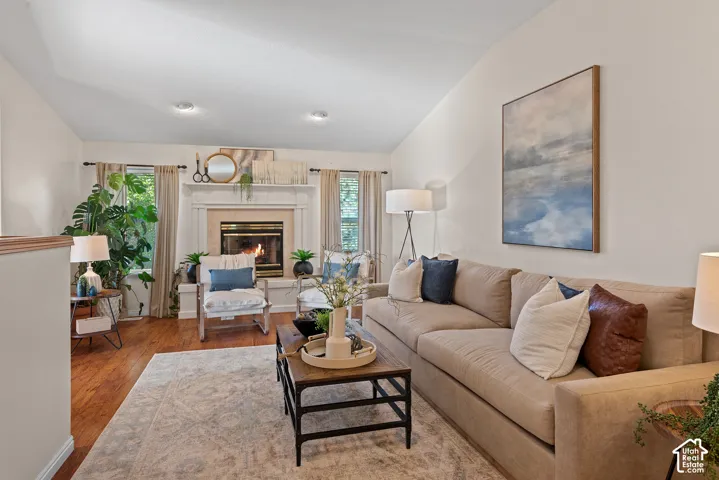 Vaulted ceiling, wood-finish flooring, recessed lighting, fireplace with mantel, and large window with natural light