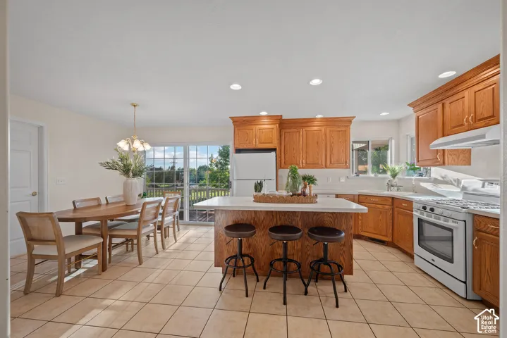 Kitchen featuring light wood-finish cabinetry, white countertops, tile flooring, a center island with bar seating, and sliding glass doors