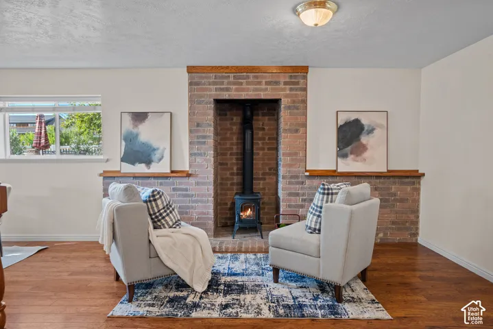 Brick fireplace with a black wood-burning stove, solid wood mantel, and wood-finish flooring