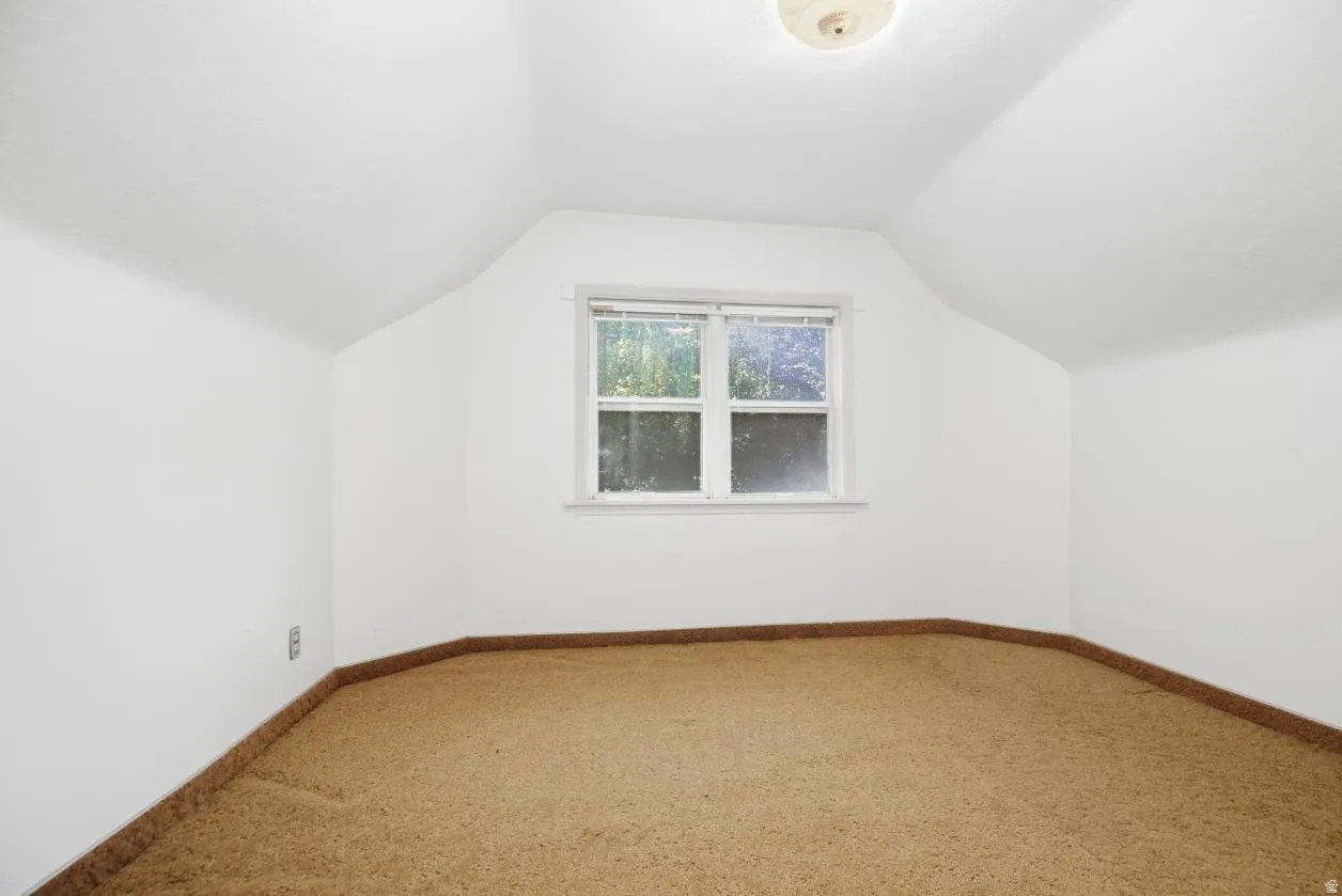 Attic room with sloped ceilings, a centered window, and a flush mount ceiling light