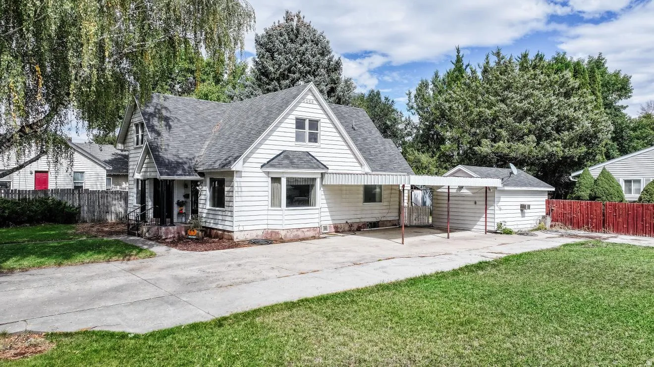 White siding exterior with a dark shingle roof, a covered front porch, and a bay window