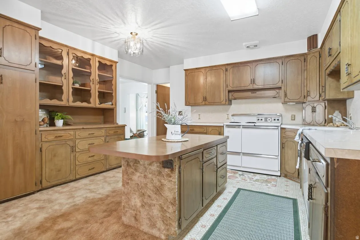 Kitchen featuring wood-finish cabinetry, a central island with a wood-finish countertop, white appliances, and built-in glass-front display cabinets