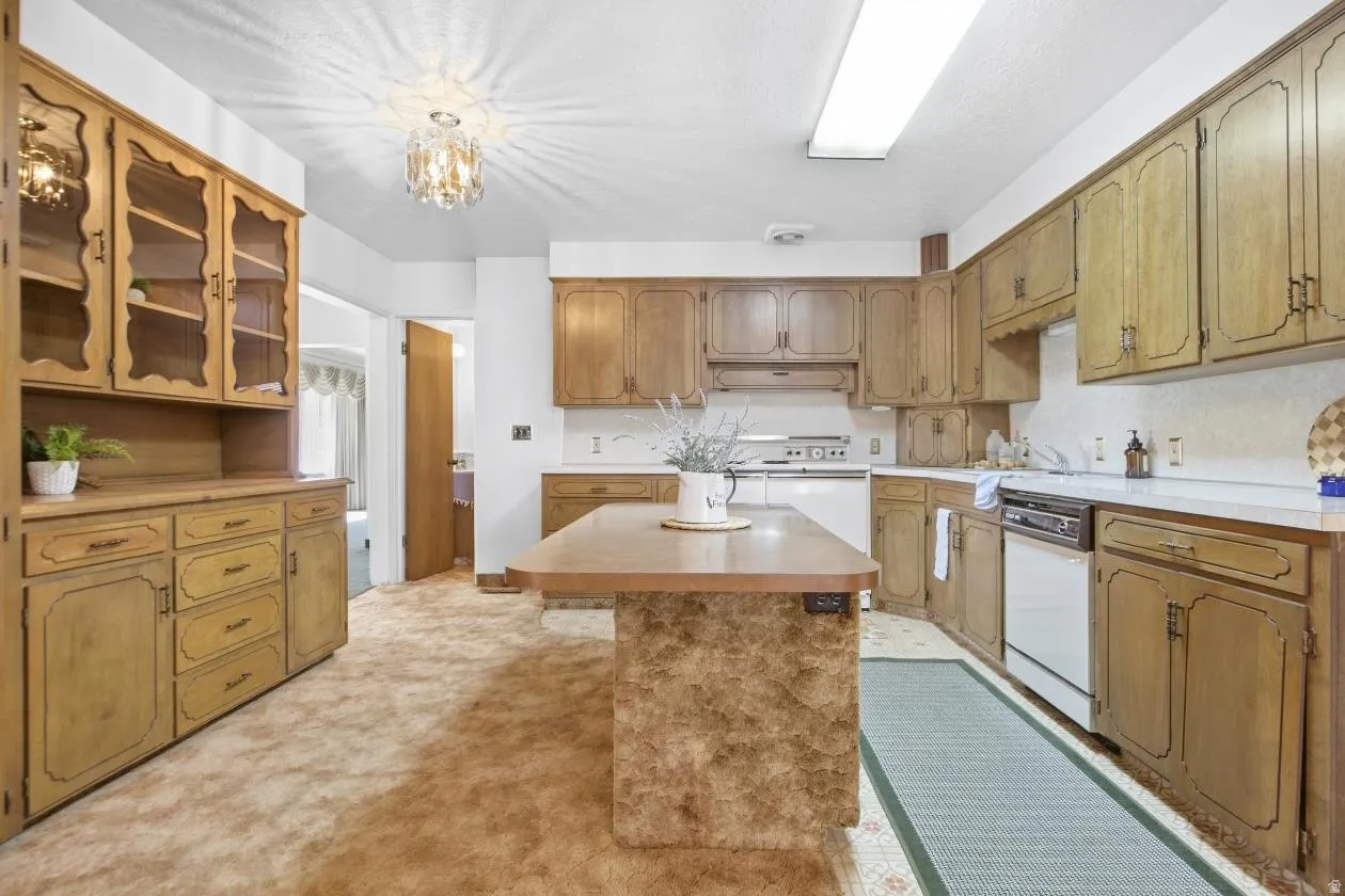Full-height cabinetry with glass-front uppers, ample counter space, integrated dishwasher, and a central island with an extended countertop