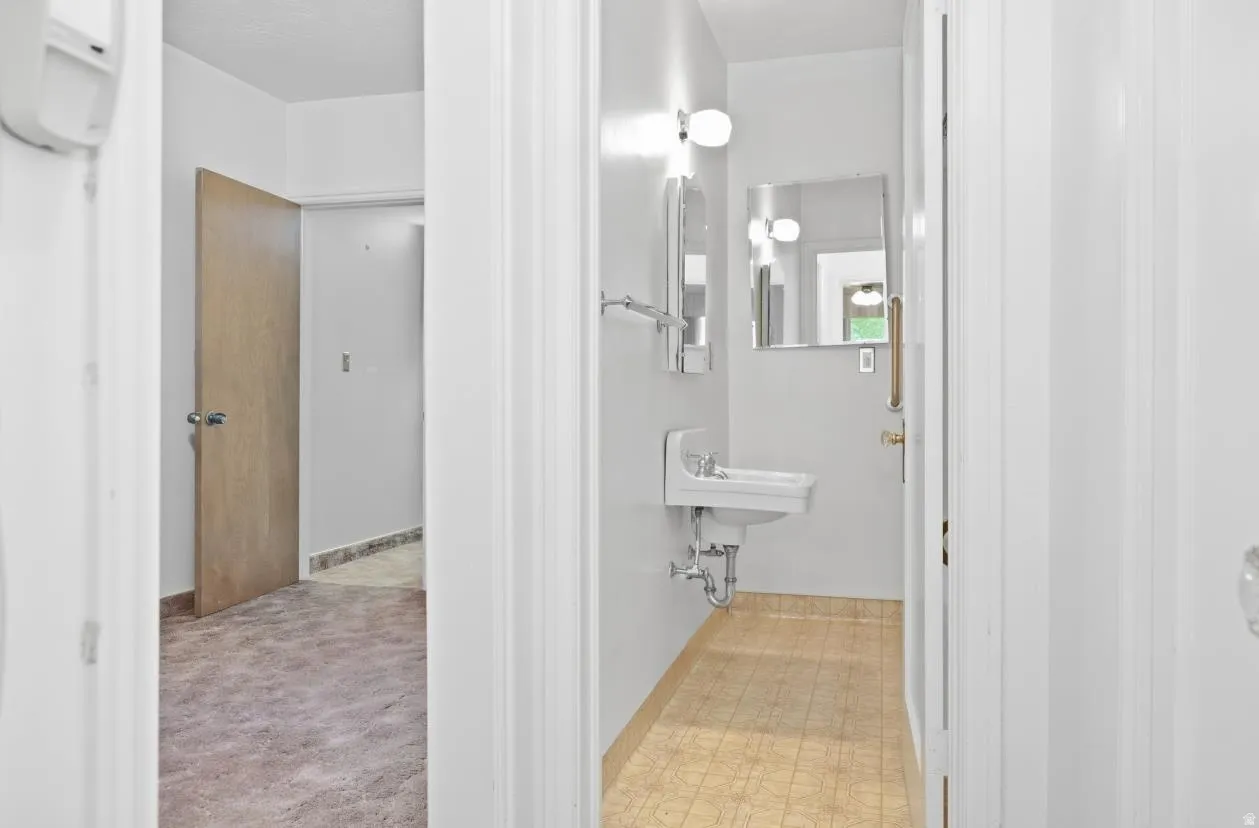 Pedestal sink with wall-mounted mirror and overhead lighting