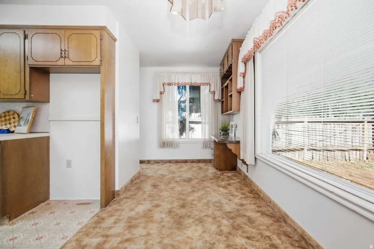 Light-filled room featuring a broad window, built-in wooden shelving, wood-finish cabinetry, and neutral wall paint