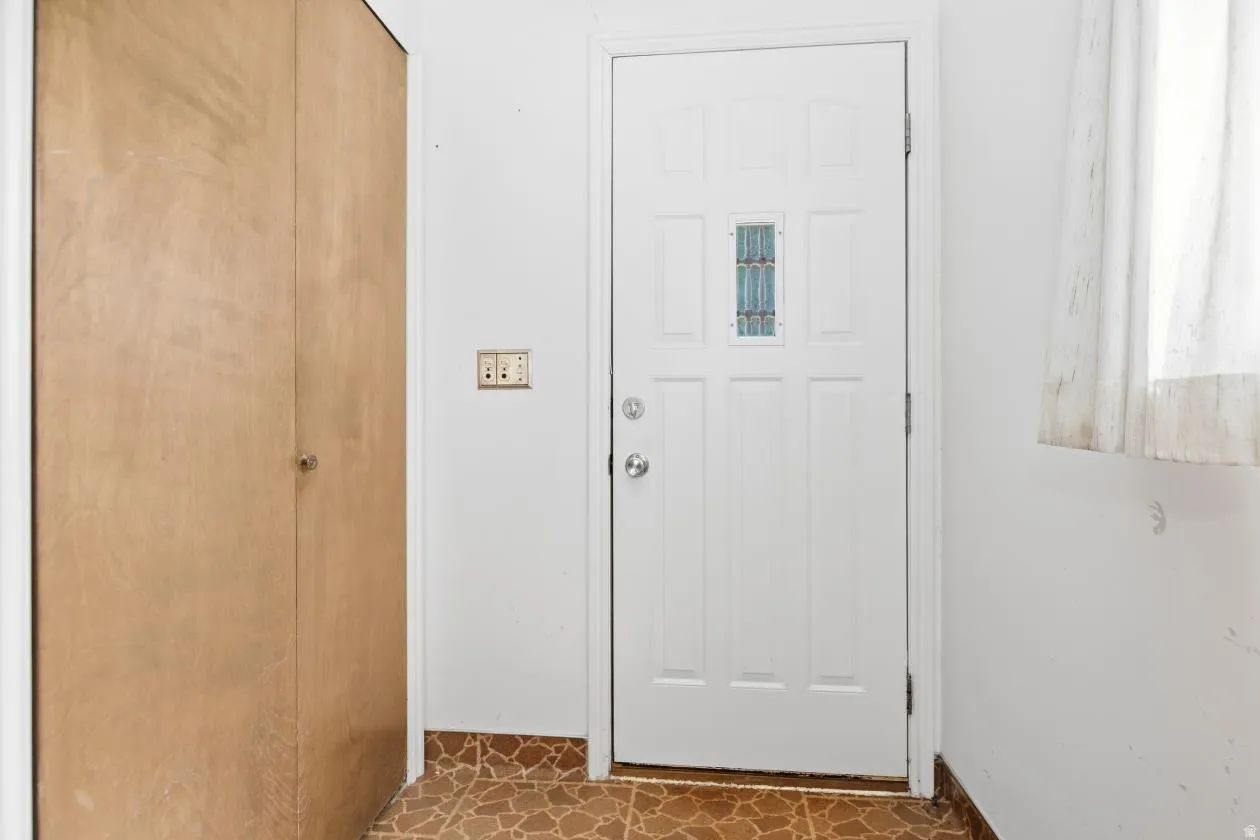 Panel door with decorative glass insert, chrome hardware, light switch, and wood-finish bi-fold closet doors- back door entrance