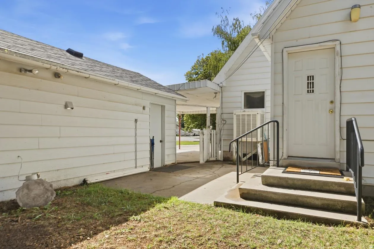 White siding exterior with an attached garage, a concrete driveway, and a covered entryway