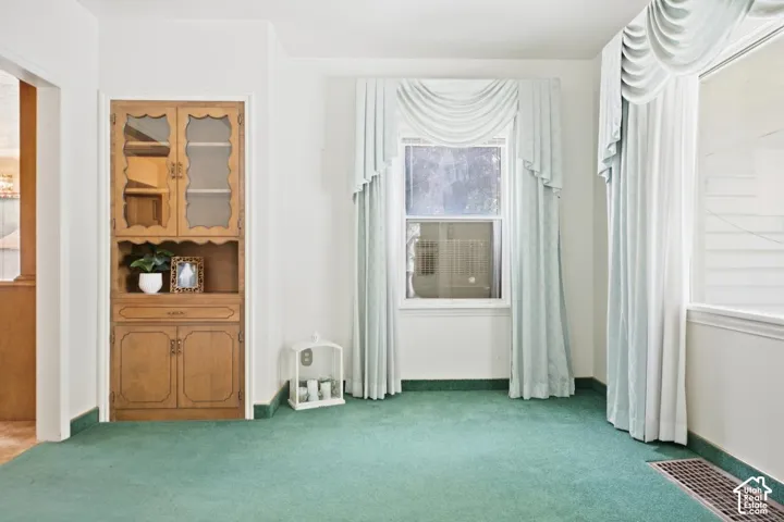Built-in wooden cabinetry with glass-paneled doors, a single window, and wall-to-wall carpeting