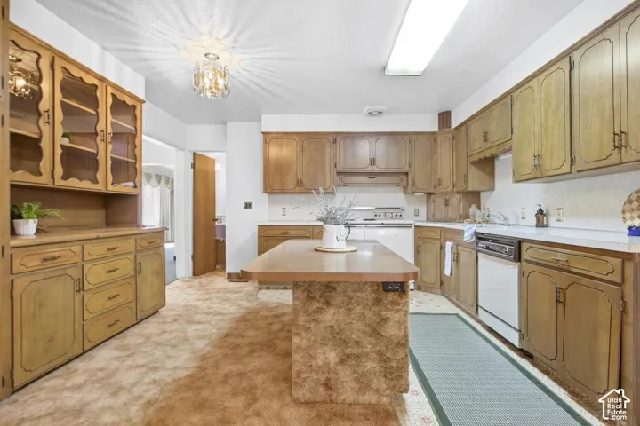 Full-height cabinetry with glass-front uppers, ample counter space, integrated dishwasher, and a central island with an extended countertop