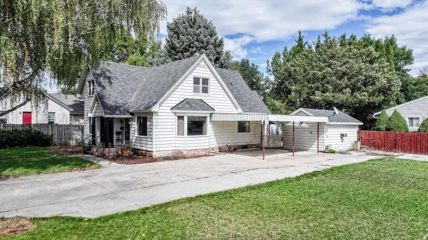White siding exterior with a dark shingle roof, a covered front porch, and a bay window