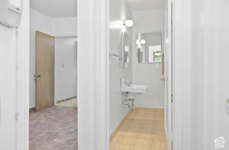 Pedestal sink with wall-mounted mirror and overhead lighting
