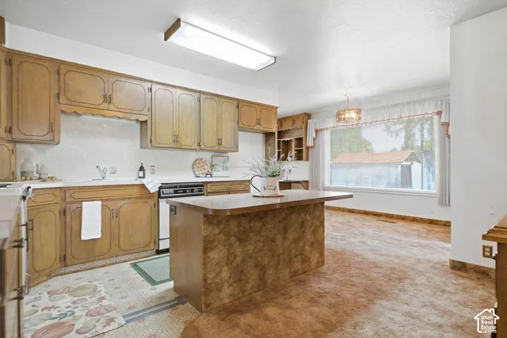 Wood-finish cabinetry, white countertops, built-in dishwasher, kitchen island with countertop, and overhead lighting fixtures