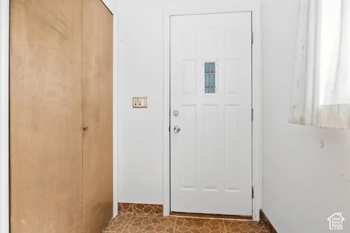 Panel door with decorative glass insert, chrome hardware, light switch, and wood-finish bi-fold closet doors- back door entrance