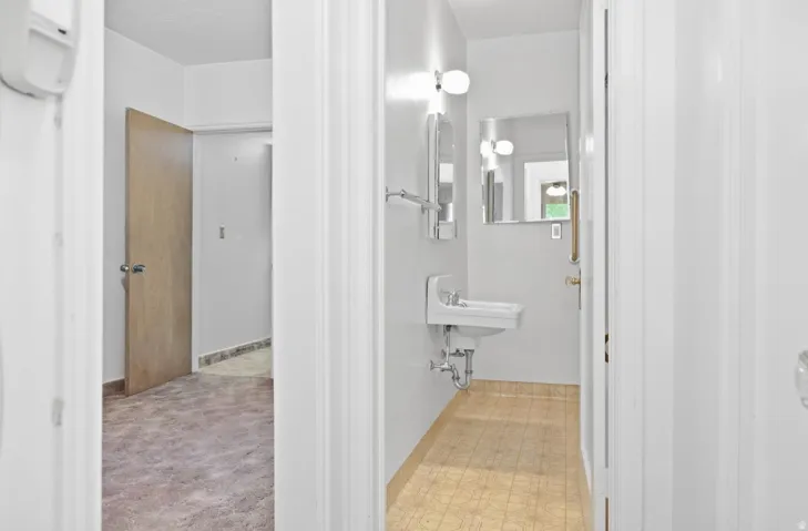 Pedestal sink with wall-mounted mirror and overhead lighting