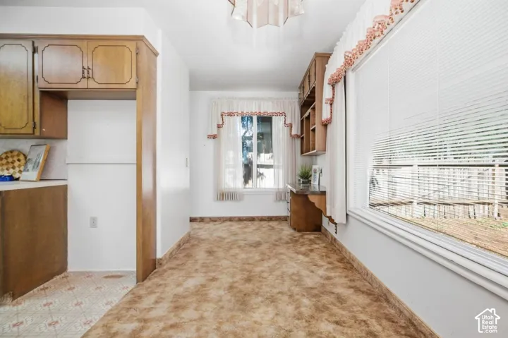 Light-filled room featuring a broad window, built-in wooden shelving, wood-finish cabinetry, and neutral wall paint