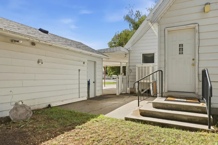 White siding exterior with an attached garage, a concrete driveway, and a covered entryway