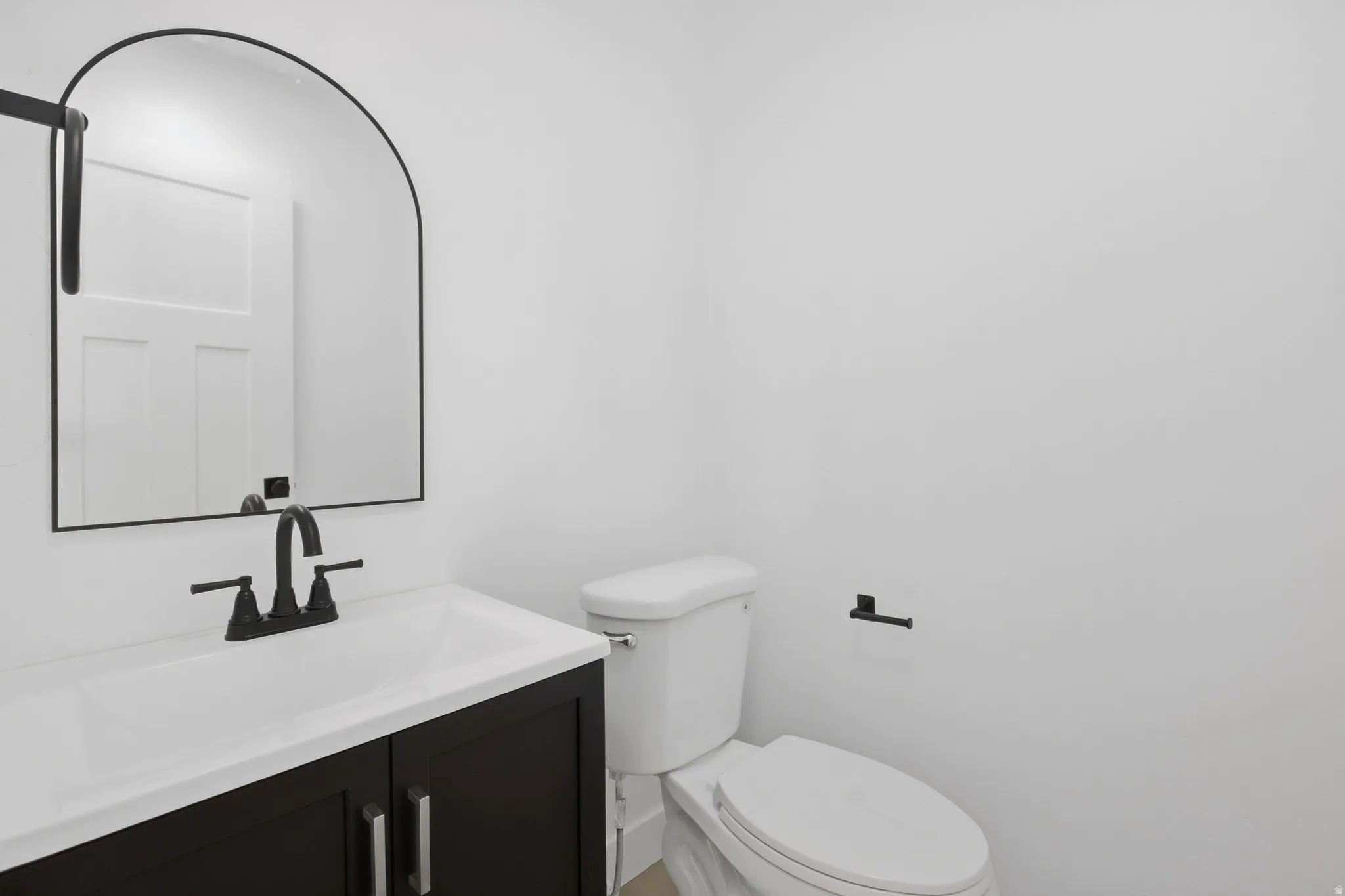 White vanity with a black base, white countertop, and integrated sink