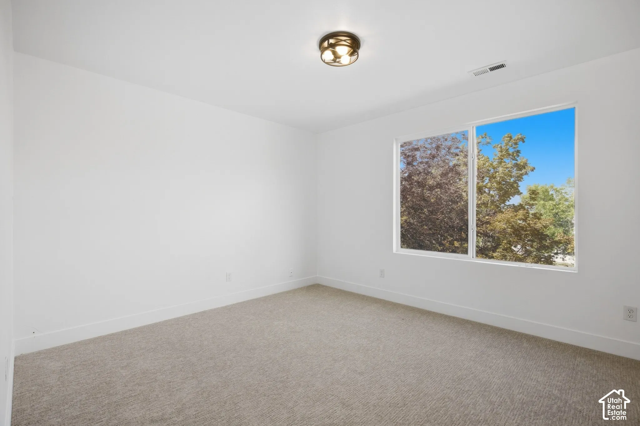 Neutral tone carpet flooring, white walls, white trim, recessed lighting, and a double-pane window