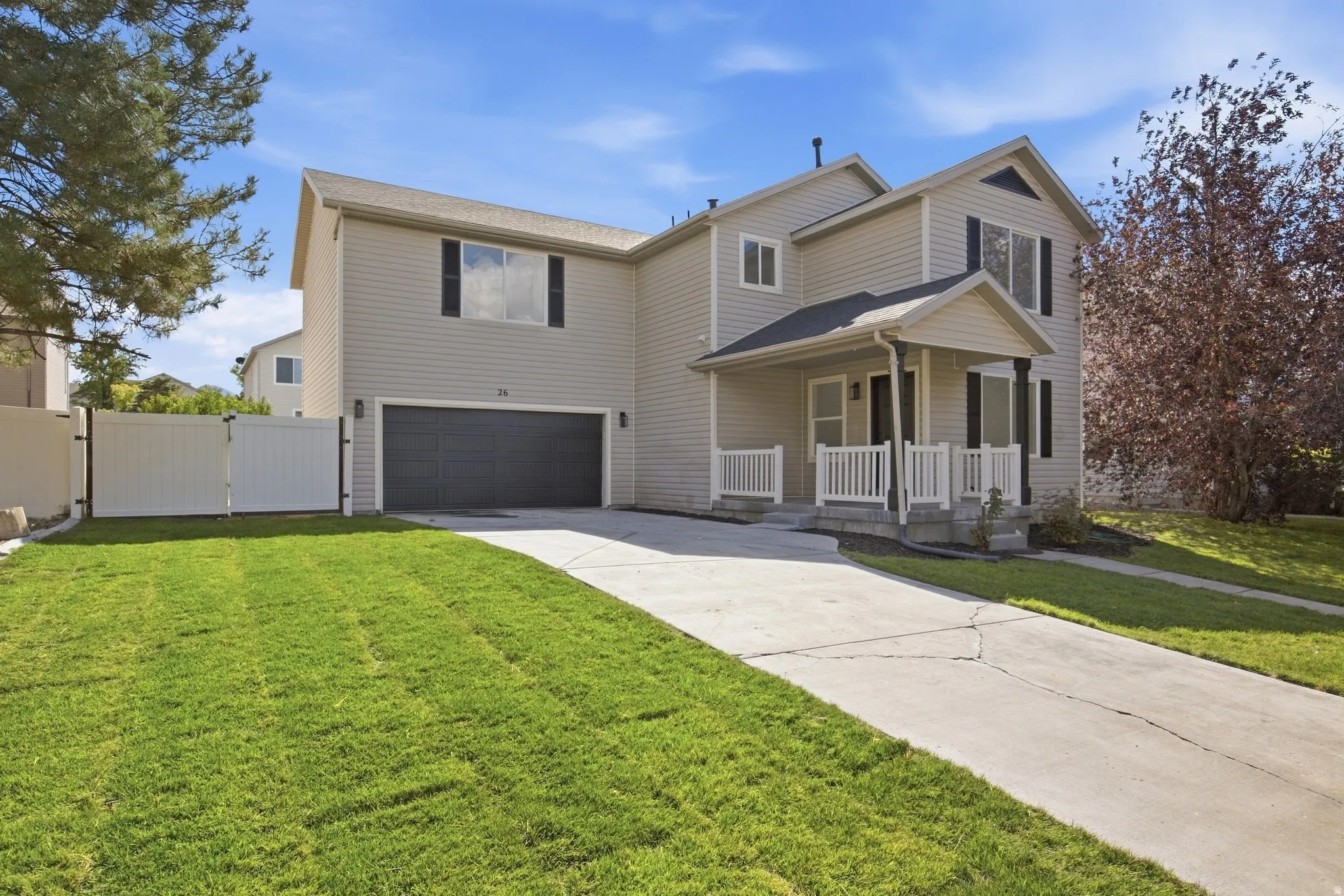 Two-story residence featuring light-toned siding, a covered front porch with white railing, and a dark garage door