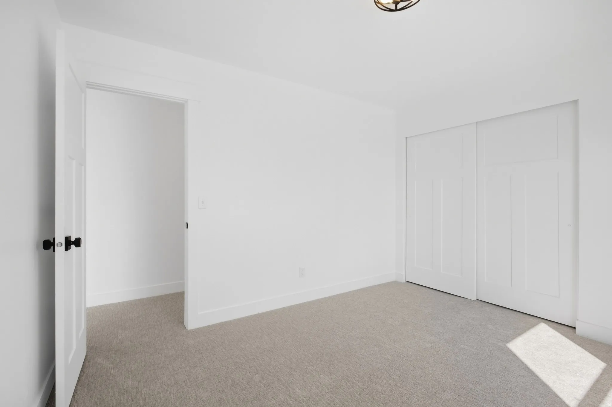 Neutral-toned carpeting, white walls, and a contemporary semi-flush ceiling fixture