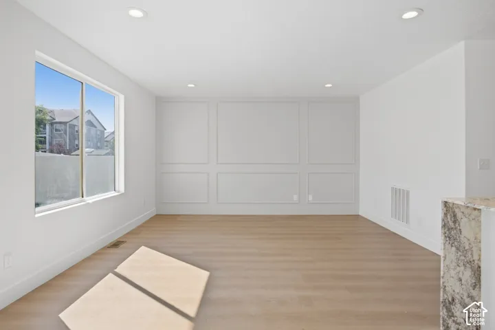 Bright interior with wood-finish flooring, recessed lighting, and decorative wall paneling