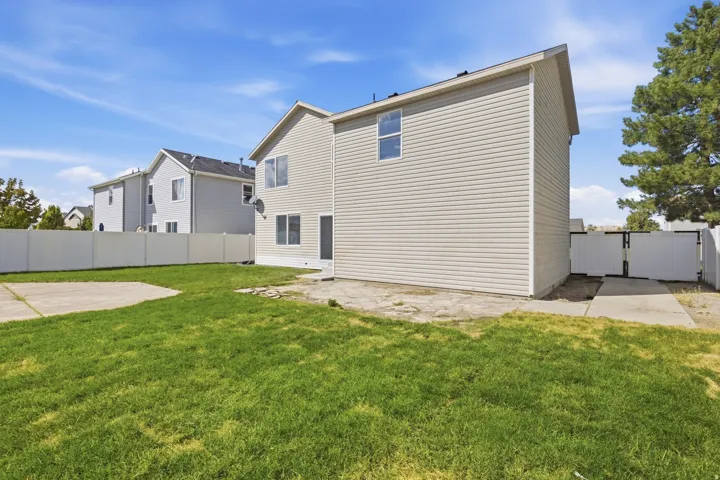 Expansive backyard featuring a concrete patio, a concrete pad, and a vinyl privacy fence