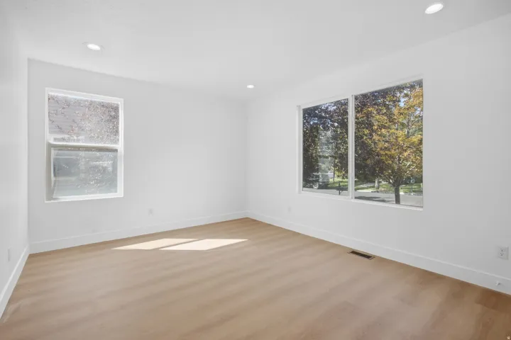 Recessed lighting, wood-finish flooring, white walls, and multiple windows