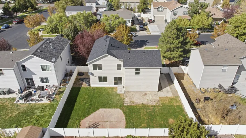 Manicured lawn with a concrete patio, bordered by a white privacy fence